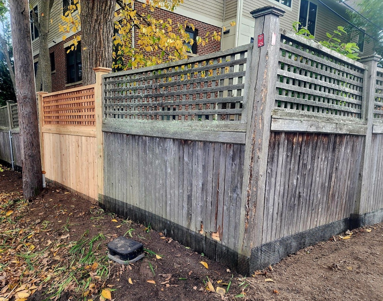 Wood privacy fence with lattice tops, a fresh wood section, and weathered panels beside a house.